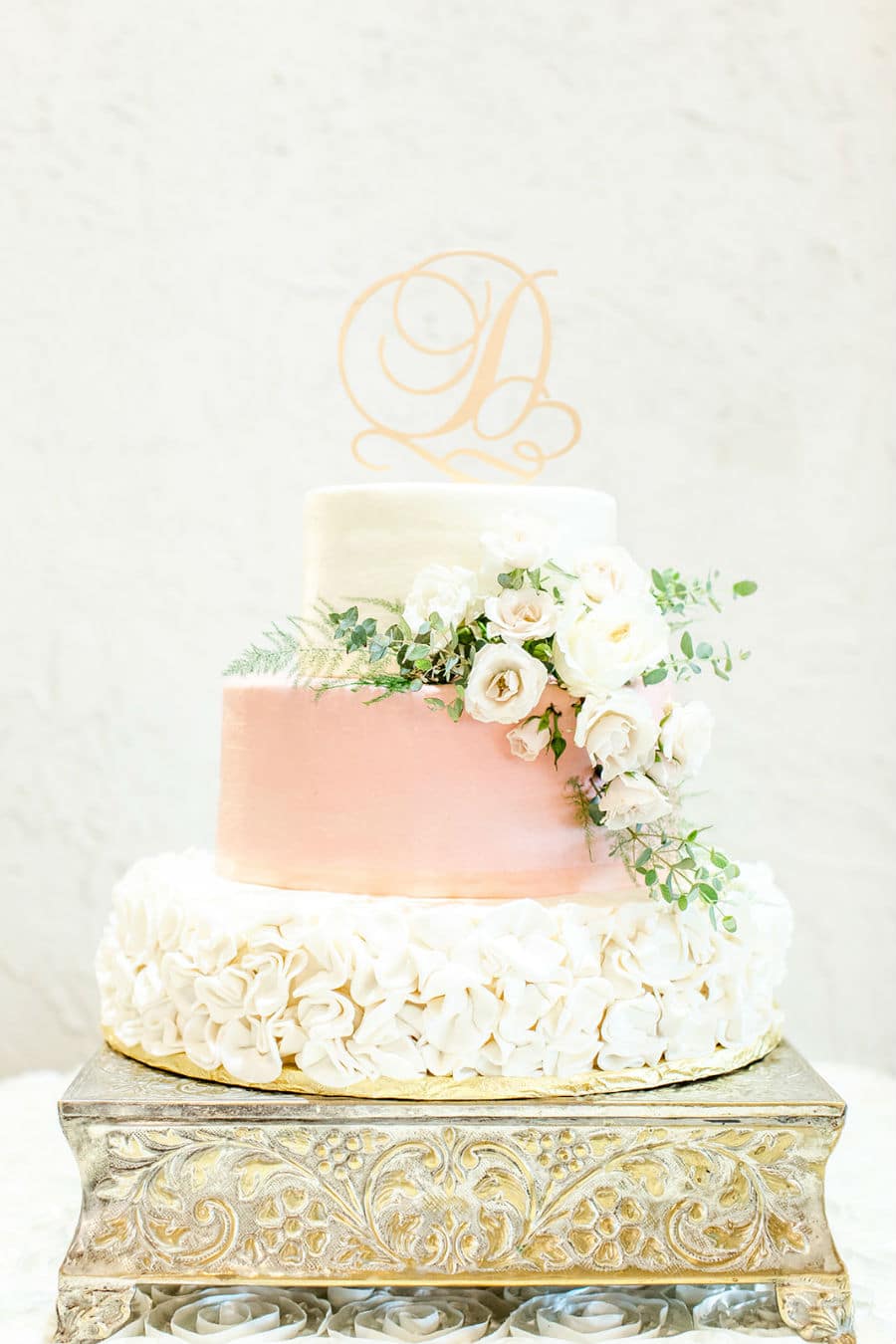 Ornate wedding cake topped with fancy letter D