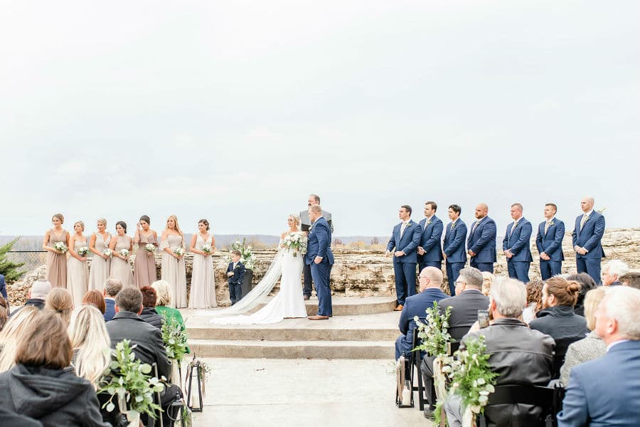 Bride and groom in ceremony with wedding party and family