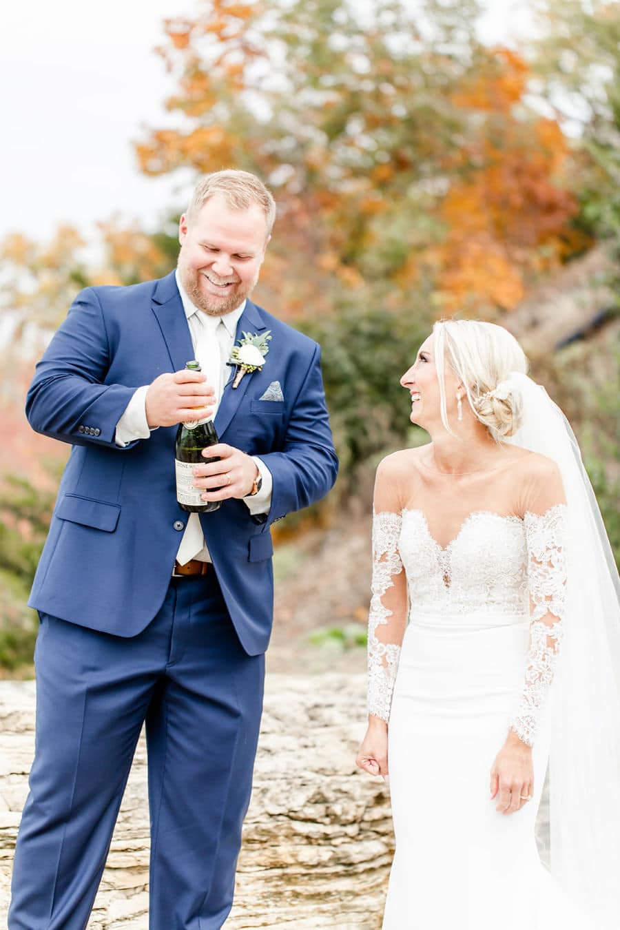 Bride and groom outdoors with bottle of champagne