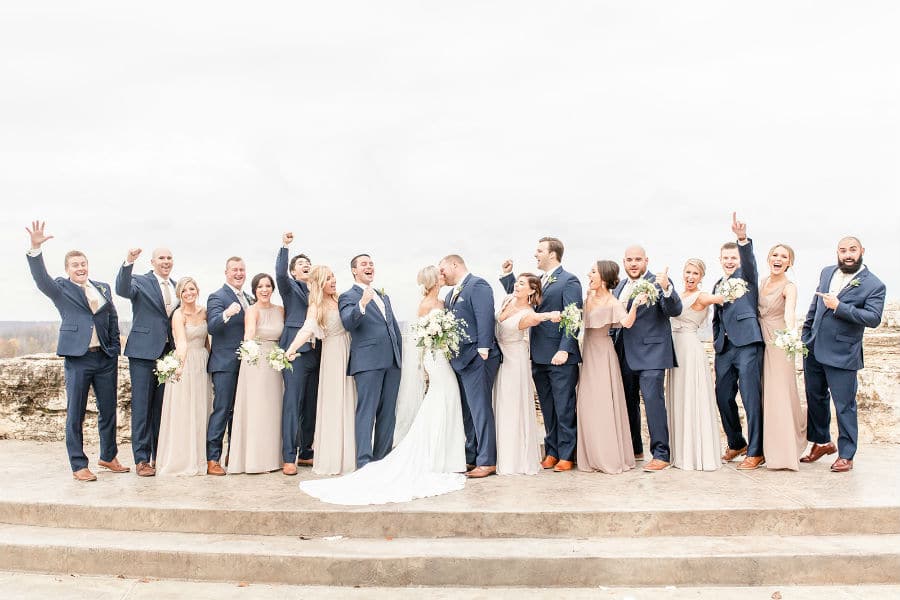 Bride and groom kiss while wedding party cheers