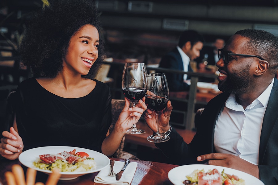 Happy couple eating dinner with wine