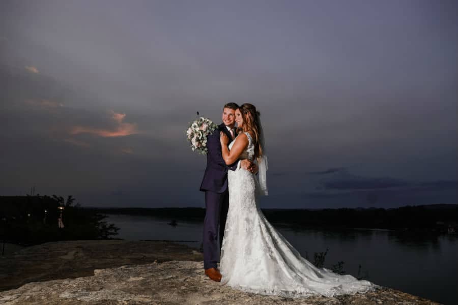 Bride and groom embrace at sunset