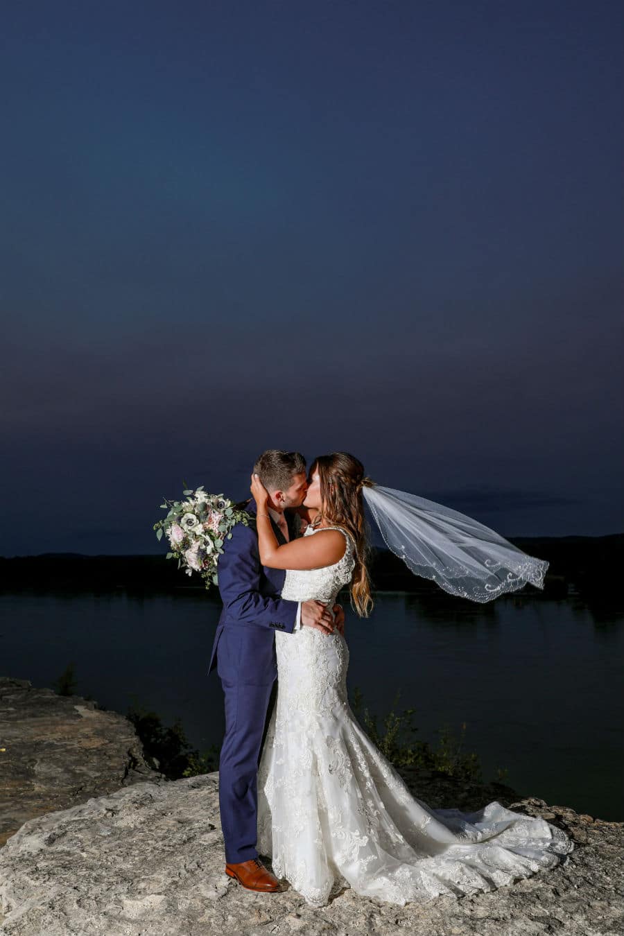 Bride and groom kiss by the river