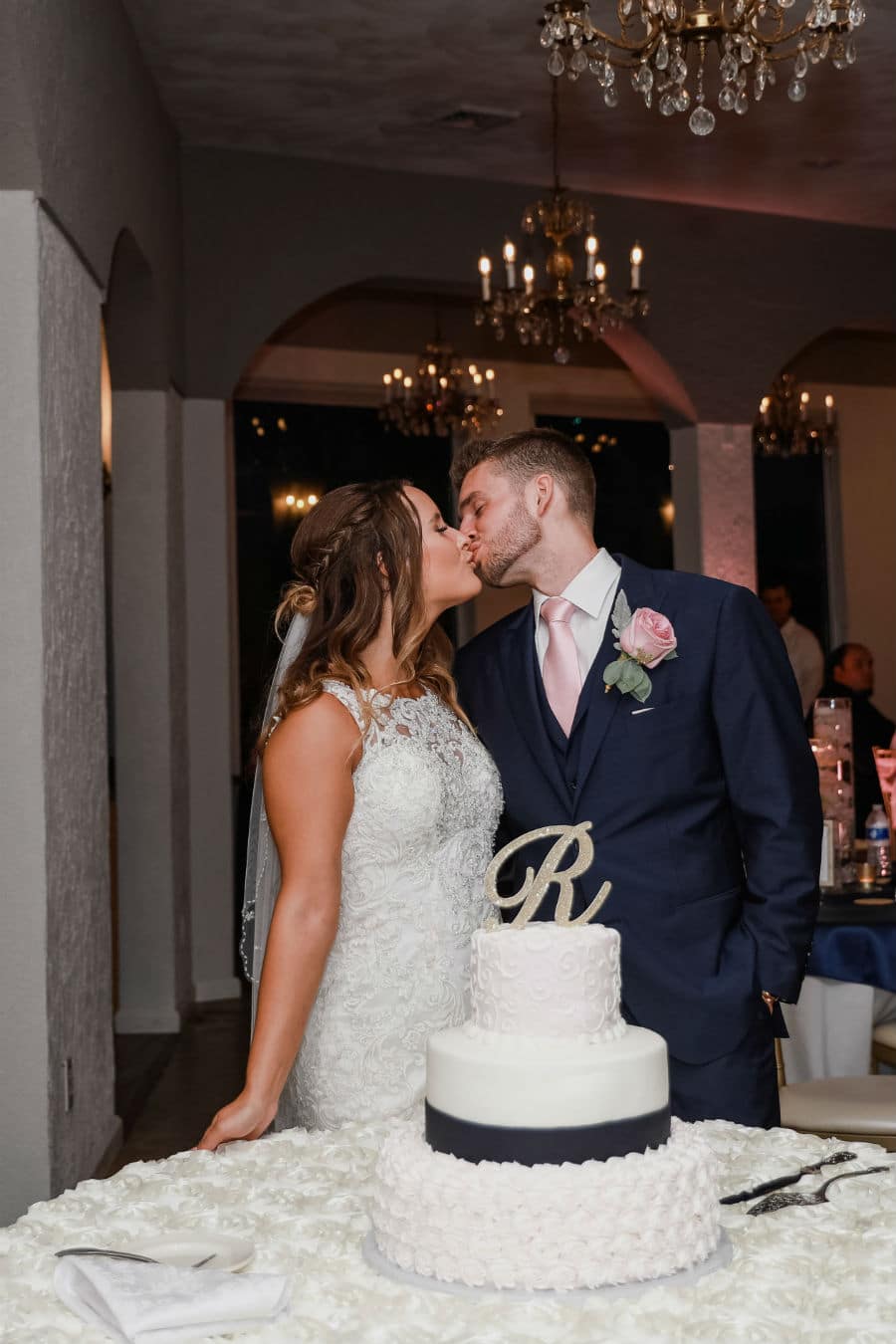 Bride and groom kiss by the cake