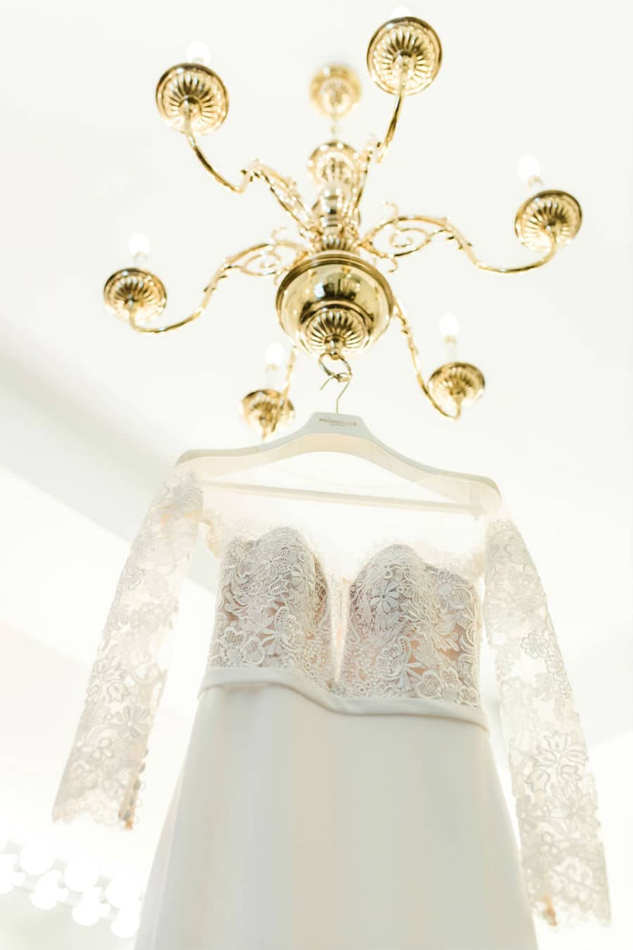 Bride's dress hanging from chandelier