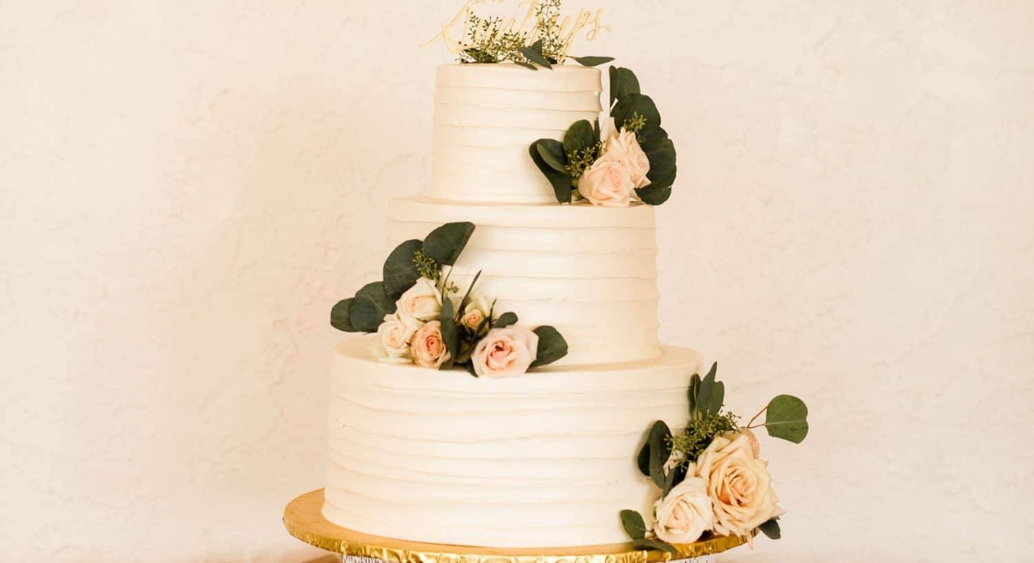 Three tier white cake with white and pink roses as decoration